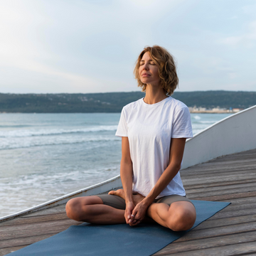 Woman practicing yoga on a mat by the ocean